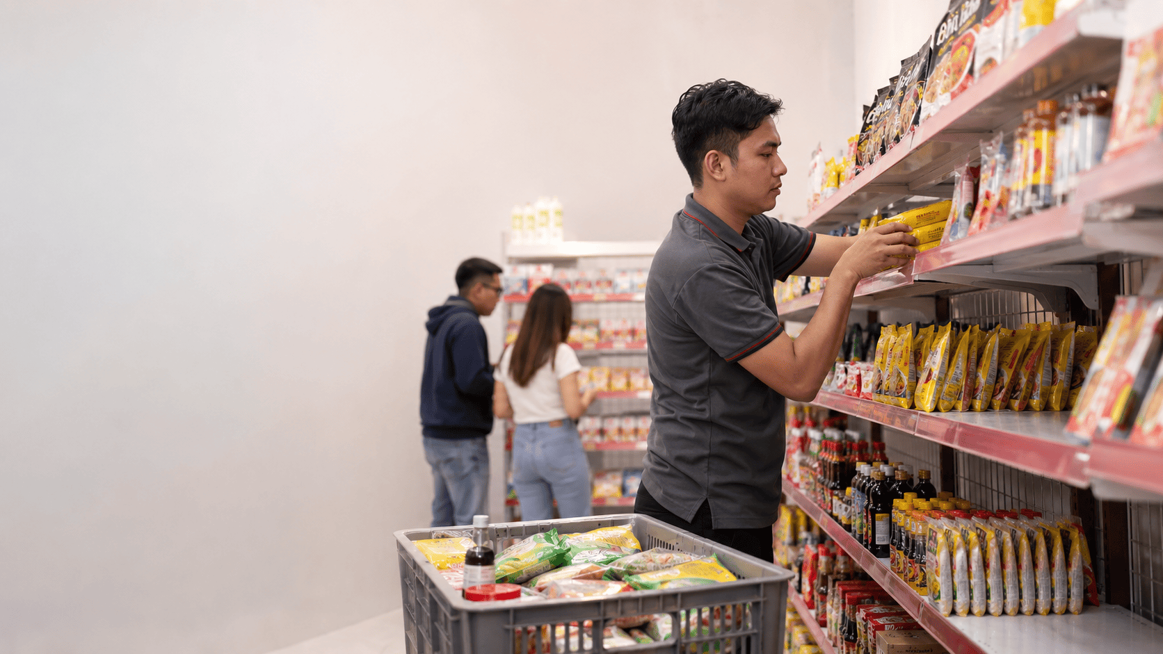 Pemilik minimarket sedang mengisi kembali rak yang hampir kosong sebagai contoh perputaran stok barang yang berjalan dengan baik.